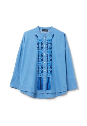 Chemise en chambray bleu clair avec un col rond, une fermeture à boutons à l'avant et une broderie navire complexe au centre avec des accents de franges.