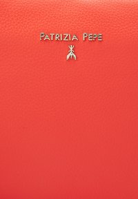 Rødt læderprodukt med tekstureret overflade og guldtonet logo, der læser "Patrizia Pepe" med et tilhørende emblem nedenunder.