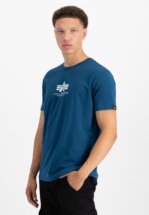 Blaues Baumwoll-T-Shirt mit kurzen Ärmeln, Rundhalsausschnitt und weißem aufgedrucktem Logo und Text auf der Vorderseite. Mit einem Etikett am linken Ärmel.