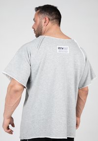 Grijze, oversized t-shirt van zachte stof, met rauwe randen en een label aan de achterkant. Loose-fitting ontwerp met korte mouwen.