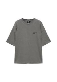 T-shirt gris oversize à manches courtes avec col rond et petit logo noir sur le côté gauche de la poitrine.