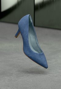 Μπλε σουέτ γόβες με μυτερή μύτη και μεσαίο τακούνι, με υφή. Το εσωτερικό είναι ανοιχτό μπλε και η σόλα είναι σε αντίθετο καφέ χρώμα.