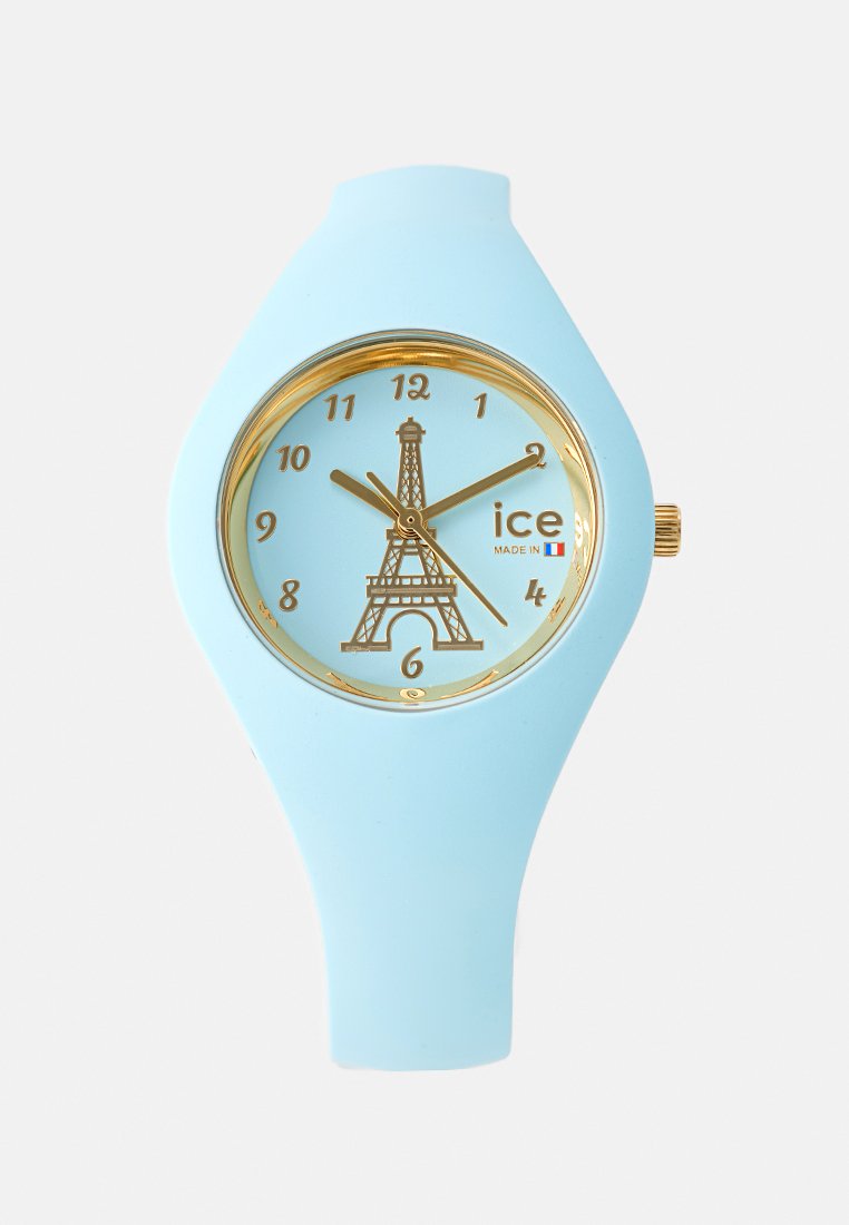 Une montre en silicone bleu clair avec un cadran doré, un design de la Tour Eiffel sur un cadran bleu pâle et des index horaires dorés.