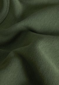 Mörkgrön ribbad tyg med en slät textur, som visar mjuka veck och en subtil lyster, vilket betonar materialets stretch och hållbarhet.