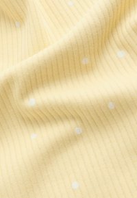 Rumeno rebrasto blago z nežnimi belimi pikicami, z mehko teksturo in rahlo spremenjeno debelino črt.