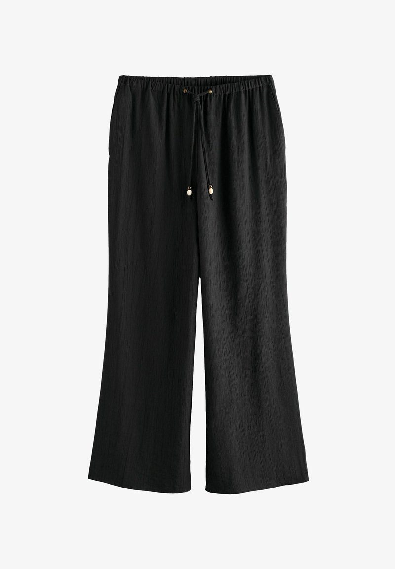 Pantalons larges noirs en tissu texturé. Dotés d'une taille élastique avec cordon de serrage et embouts en métal.