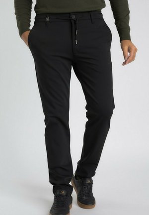 Pantalons slimming noirs sur mesure, avec un design épuré, une fermeture à bouton et à cordon, et des poches latérales.