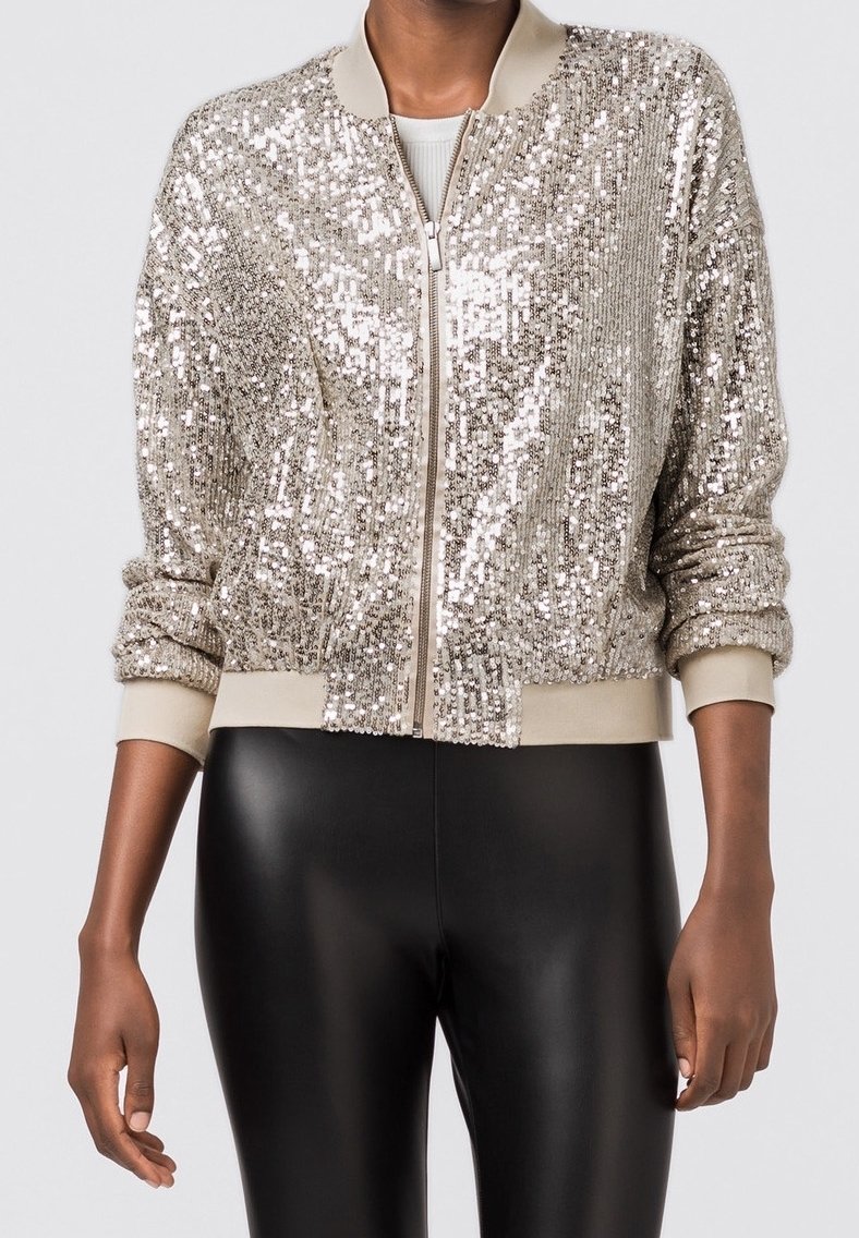 Silberne Pailletten-Bomberjacke mit gerippten Bündchen und Kragen. Verfügt über einen Reißverschluss vorne und eine strukturierte Oberfläche. Tragen Sie sie über schwarzen Leggings.