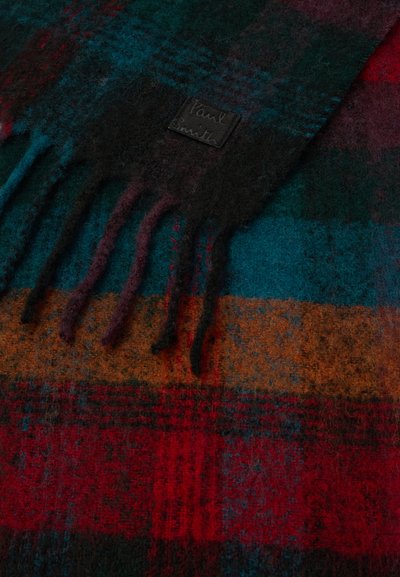 Bufanda de cuadros con colores verde oscuro, rojo, negro y naranja. Textura suave con bordes desflecados. Incluye una pequeña etiqueta negra.