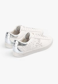 Witte leren sneakers met zilveren metalen accenten, textuurzool, geperforeerd zijontwerp en detail van doodskop en gekruiste beenderen.