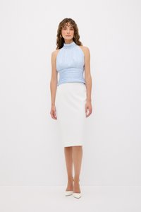 Top azzurro chiaro con collo all'americana e pieghe, abbinato a una gonna midi bianca aderente. I tacchi bianchi a punta completano l'outfit.