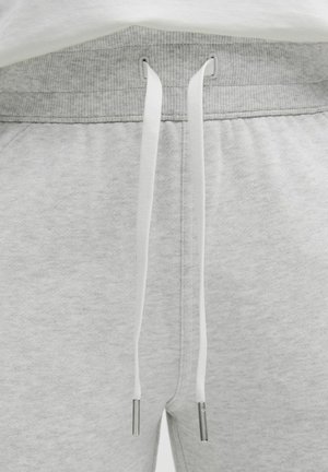 Lichtgrijze joggers met een ribbelband, voorzien van witte trekkoorden met metalen uiteinden en een zachte, gestructureerde stof.