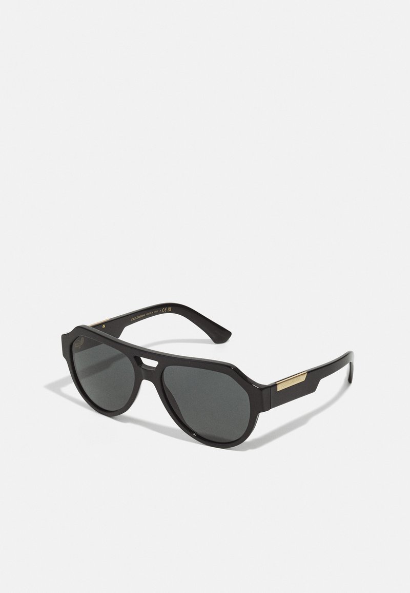 Black sunglasses with a geometric frame, tinted lenses, and gold accents on the temples. Smooth plastic material with a matte finish.