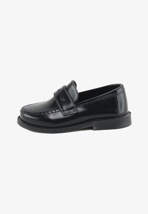 Mocasín tipo penny loafer de cuero negro con detalles cosidos y suela gruesa de goma, mostrado de perfil sobre fondo blanco.