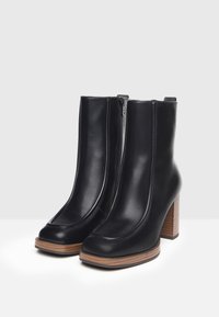 Black leather ankle boots with a rounded toe, side zipper, and a stacked wooden heel. Smooth texture with subtle stitching detail.