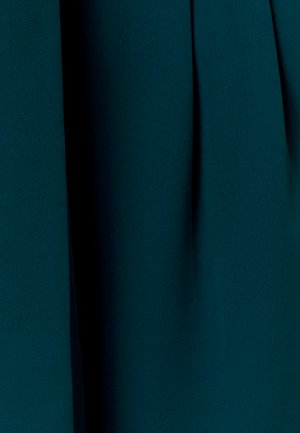 Tessuto verde petrolio scuro con pieghe verticali e una texture morbida che crea profondità ombreggiata e un effetto di caduta fluida.