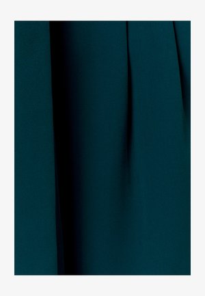 Tessuto verde petrolio scuro con pieghe verticali e una texture morbida che crea profondità ombreggiata e un effetto di caduta fluida.