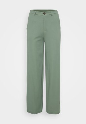 Hlače širokega kroja iz svetlo zelene tkanine z gladko teksturo. Imajo sprednje zapiranje na gumb in dva stranska žepa.