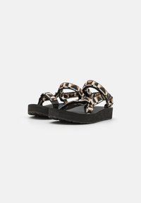 Sandalias de plataforma negras con una correa estampada que presenta formas geométricas en naranja, blanco y negro. Suela de goma texturizada para mayor agarre.