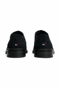 Donkerblauwe suède schoenen met een gladde afwerking, zwarte rubberen zolen en een klein vlaglogo aan de zijkant. Heeft een reliëf merknaam op de hiel.