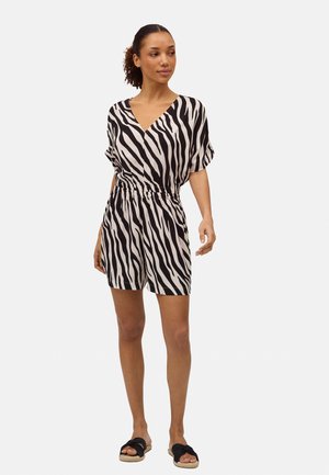 Mono de estampado de cebra en blanco y negro con escote en V, mangas cortas y cintura elástica, combinado con sandalias deslizantes negras.