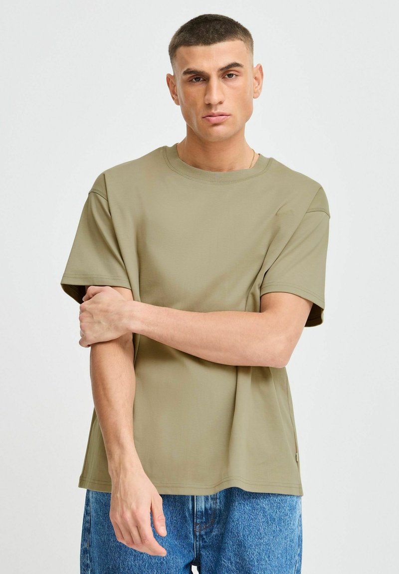 Olijfgroene T-shirt met korte mouwen en een ronde hals, gemaakt van gladde stof, met een relaxte pasvorm en zichtbare stikseldetails.