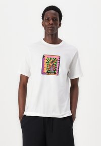 White cotton T-shirt with a square graphic featuring a colorful design and text, set against a striped background. Short sleeves, crew neck.
