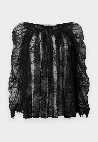 Mustlane pitsakk, millel on läbipaistev kangas, puhvsiolid, volditud disain ja laineline alläär. Komplekse lillemustrid kogu ulatuses.