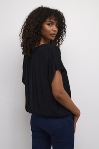 Black, loose-fitting top with short sleeves, textured fabric, and a round neckline, paired with dark blue jeans, viewed from the back.