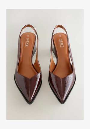 Burgundy patent leather slingback heels with pointed toe, cutaway sides, and a low heel. Features a tan insole with brand logo.