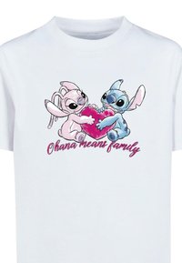 Hvid bomulds-t-shirt med tegneseriefigurer, der holder et pink hjerte. Teksten nedenfor lyder "Ohana betyder familie" i kursiv pink skrift.