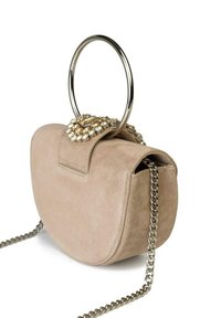 Borsa in suede beige con manico circolare in argento e tracolla in catena. Presenta un accento di gioiello sulla chiusura. Forma rotonda con texture morbida.