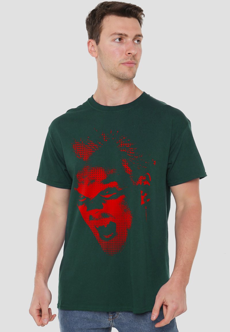 Man wearing dark green t-shirt with large red graphic of an expressive screaming face on front, looking to his right.