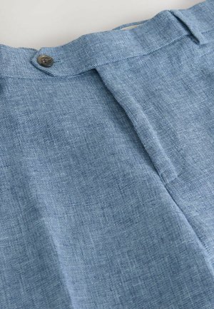 Vaaleansininen denim-kangas, jossa on sileä pinta, keskellä laskos ja vyötäröllä yksi metallinen nappi kiinnitystä varten.