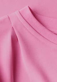 Tessuto rosa con una superficie liscia e un leggero motivo a coste. Presenta un colletto rotondo e decorazioni plissettate sulle spalle.