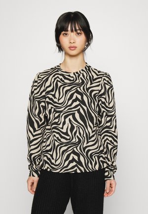 Camisola de mangas compridas em padrão zebra beje e preto, com decote redondo e mangas bufantes franzidas, combinada com calças pretas de malha canelada.