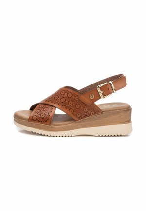 Sandalo in pelle marrone con tomaia perforata, cinturini incrociati, fibbia regolabile, tacco in legno e suola in gomma beige con grip testurizzato.