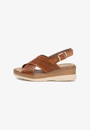 Sandalo in pelle marrone con tomaia perforata, cinturini incrociati, fibbia regolabile, tacco in legno e suola in gomma beige con grip testurizzato.