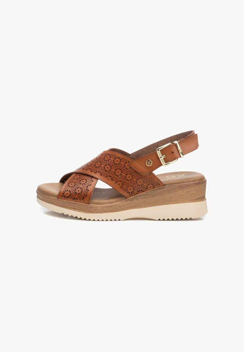 Sandalo in pelle marrone con tomaia perforata, cinturini incrociati, fibbia regolabile, tacco in legno e suola in gomma beige con grip testurizzato.