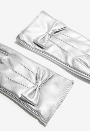 Srebrne skórzane rękawiczki o gładkiej fakturze, z ozdobną kokardą i fałdami. Design jest elegancki i smukły.