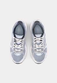 Scarpe atletiche a rete di colore azzurro chiaro con accenti bianchi, dotate di punta arrotondata, design con lacci e suola testurizzata per supporto e trazione.