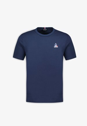Marineblauwe katoenen t-shirt met korte mouwen, ronde hals en een klein logo met een haan en driekleurige accenten op de kraag.