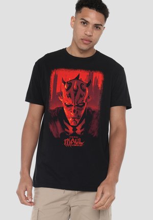 Young man wearing black t-shirt with red graphic of Star Wars' Darth Maul face and the text "Maul Shadow Lord" on front.