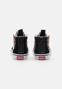 Černé vysoké tenisky se vzorovanou textilií, bílou gumovou podrážkou a zadním zipem. Obsahují červené logo na patě a kontrastní bílé švy.