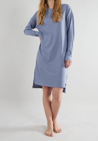 Camicia da notte a maniche lunghe in tessuto azzurro chiaro, scollatura rotonda, fessure laterali, con logo del brand discreto sul petto e una vestibilità comoda.