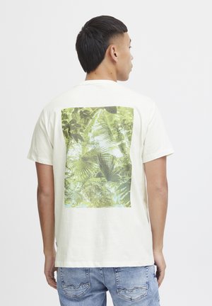 Cremefarvet bomulds T-shirt med en stor grøn tropisk bladmønster grafik på ryggen. Korte ærmer, standard rund hals design.