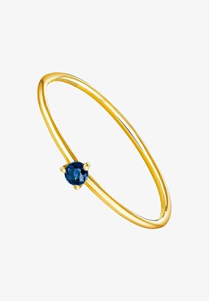 Brazalete de oro que presenta una gema azul redonda y facetada, engastada con cuatro garras; superficie lisa y pulida, forma circular.