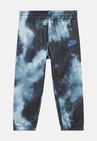 Calças de treino Nike em padrão tie-dye azul e preto. Apresentam uma cintura elástica e um pequeno logótipo azul na perna esquerda. Tecido suave.