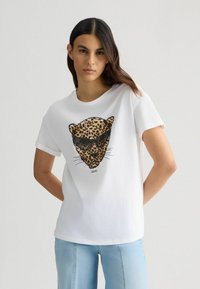 T-shirt bianca a maniche corte con grafica di faccia di leopardoche in marrone e nero, occhiali da sole e baffi; vestibilità rilassata e texture liscia.