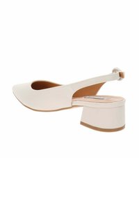 Zapato tipo slingback en faux cuero blanco, con puntera redonda y tacón bajo en bloque. Presenta un lado con corte y una sutil correa en el tobillo.
